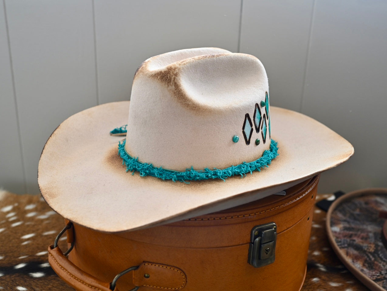 Ezra ivory felt cowboy hat with painted branding and Kingman turquoise accents.